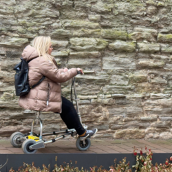 Melanie Schembor testet die Barrierefreiheit des Klosters Memleben mit einem Travel Scooter auf einem gepflasterten Weg in der historischen Klosterkirche.