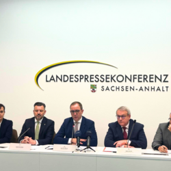 Frau Dr. Prof. Ariane Berger, Geschäftsführendes Präsidialmitglied des Landkreistages Sachsen-Anhalt, Landrat Mansfeld-Südharz André Schröder, Landrat Salzlandkreis Markus Bauer, Landrat des Burgenlandkreises und Präsident des Landkreistages Sachsen-Anhalt, Götz Ulrich (v.l.n.r.), sitzen auf einem Podium bei der Landespressekonferenz Sachsen-Anhalt. Sie sprechen über die Verfassungsbeschwerde zur finanziellen Mindestausstattung der Landkreise gemäß Artikel 28 Grundgesetz.